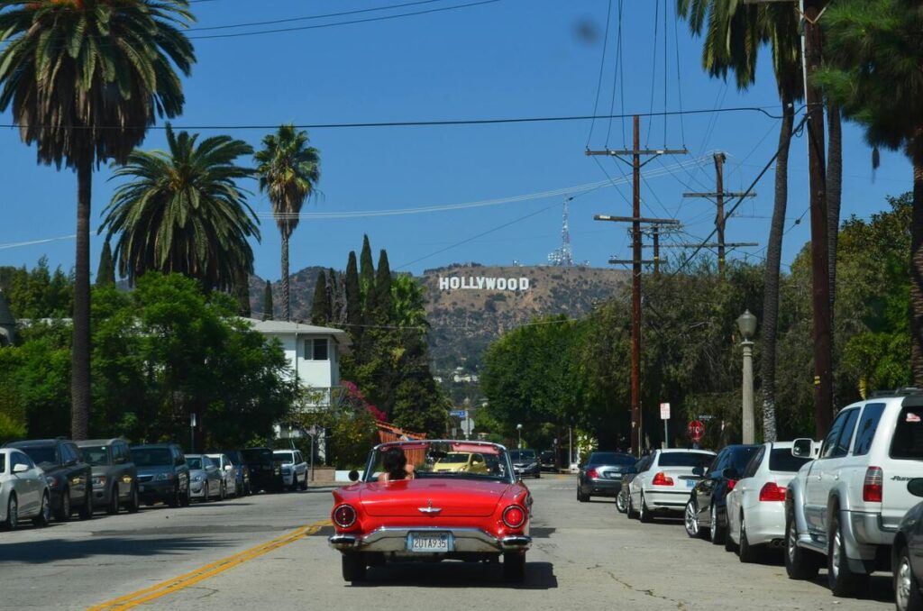 Magnifique photo de Los Angeles sous un parfait ciel bleu, une décapotable vintage, les palmiers et le panneau hollywoord au loin